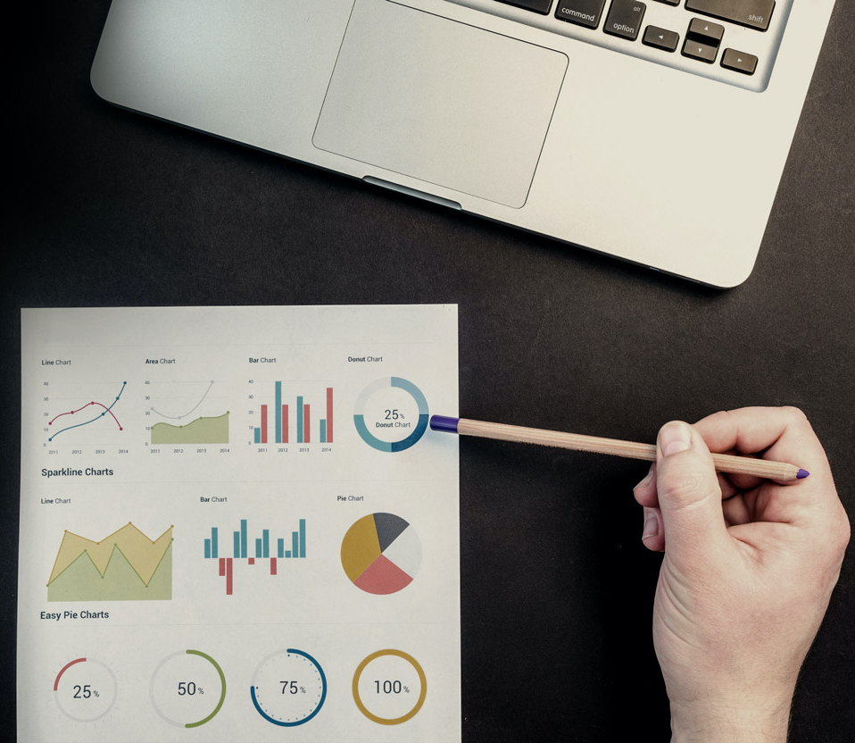 hand of person working at a desk holding a pencil while review data visualizations on a paper